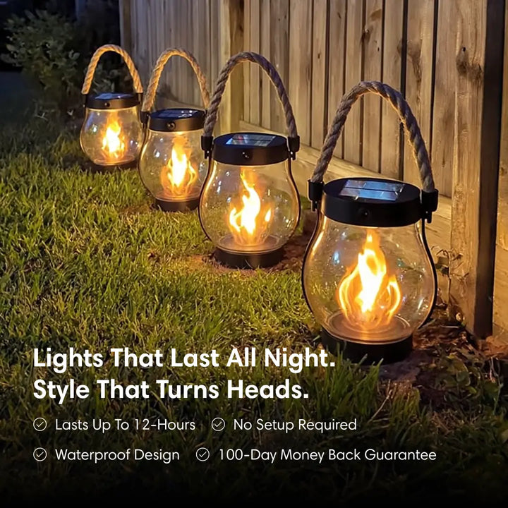 Black solar lantern with a flame effect, rope handle and solar top shown on a lawn at night.