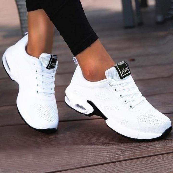White breathable mesh sneakers with black outsole edges and a visible air-cushion window, worn with black leggings on wood planks. 3
