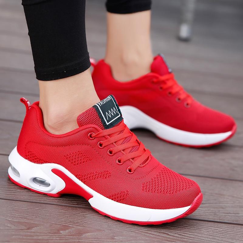 Close side view of red mesh sneakers with white air-cushion soles and red laces, worn with black leggings. 5
