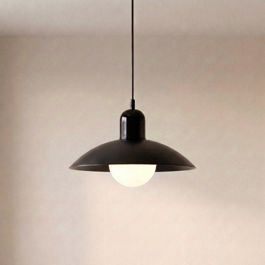All-black pendant lamp with a glossy dome cap, wide dish shade and a lit frosted white globe hanging from a black cord. 24
