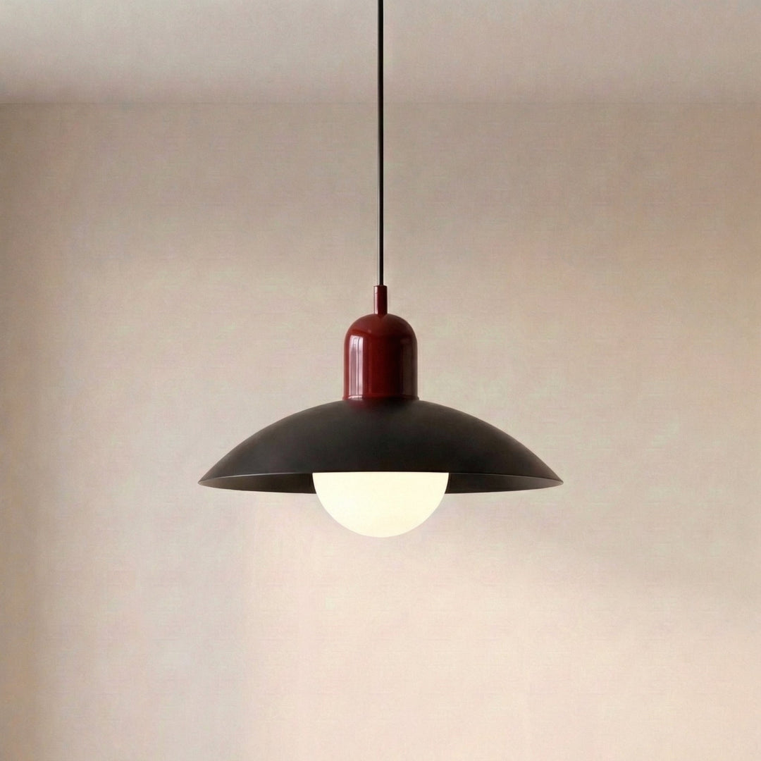 Pendant lamp with a dark wide dish shade, glossy deep red cap and a lit frosted white globe against a neutral wall. 23