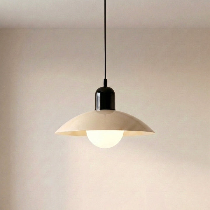 Beige Macaron Pendant Light against a wall with the bulb lit.