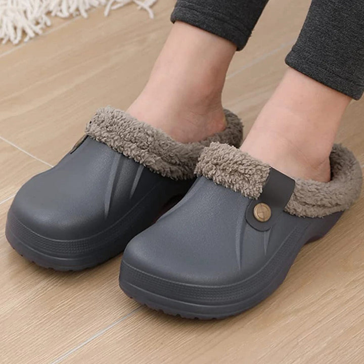 Close-up of feet wearing gray fur-lined clogs on a light wood floor 8