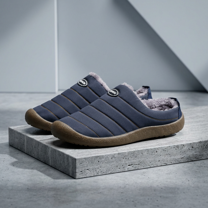 Navy blue quilted slippers with brown soles staged on a rough concrete block against a gray wall 18