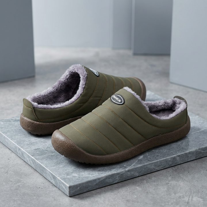 Olive green slippers with plush gray lining displayed on a marble slab in a modern gray setting 17