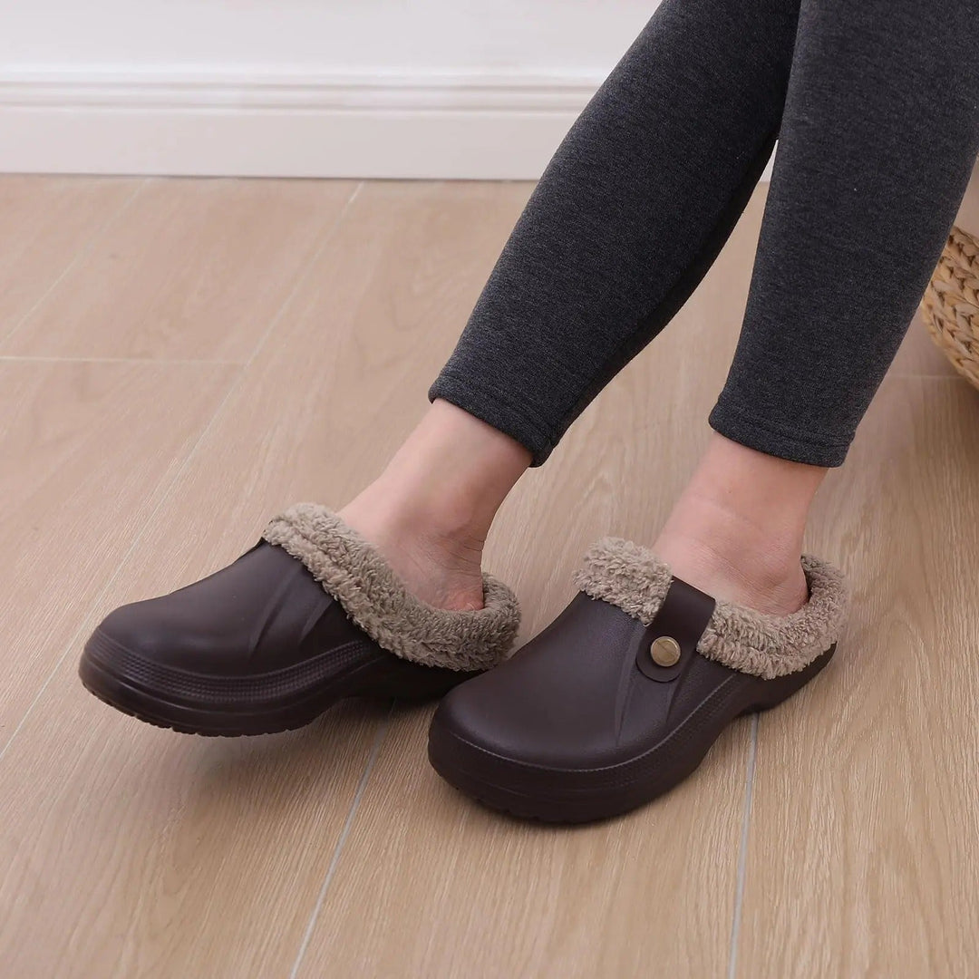 Person in gray leggings wearing brown fur-lined clogs while seated on a wood floor 7