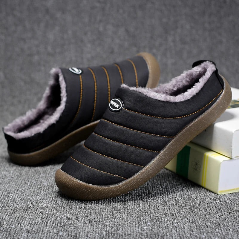 Black slippers with orange stitching and gray fleece lining, one tilted against books beside the other 9