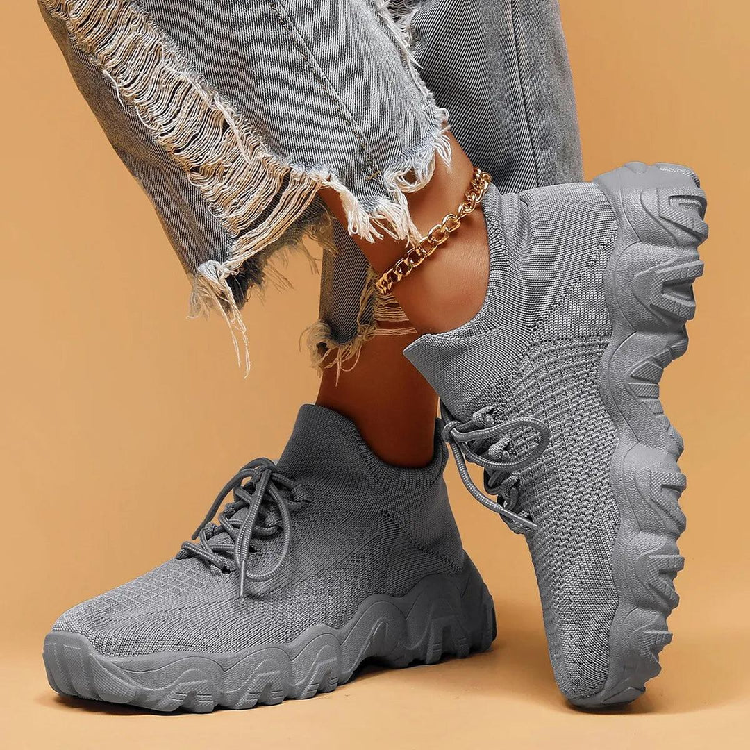 Model's legs in solid gray knit sneakers, one foot tilted to show the chunky lugged sole and side knit texture. 45