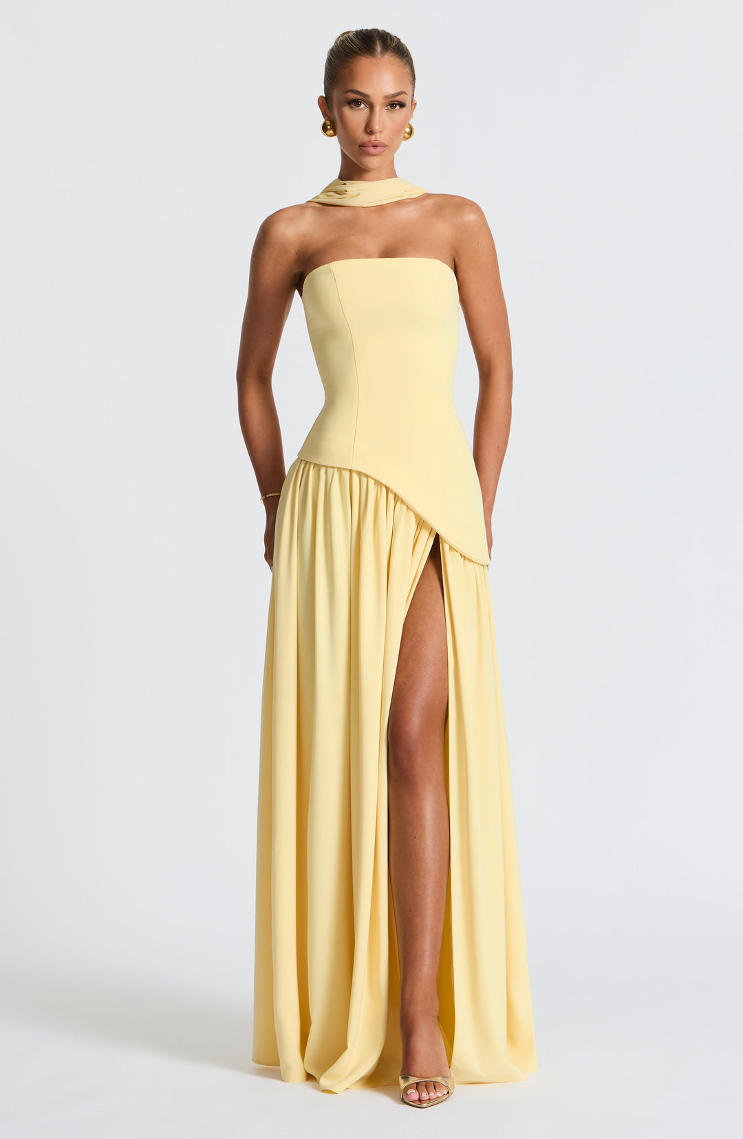 Front view of the pale yellow strapless dress with fitted bodice, gathered skirt and high slit.