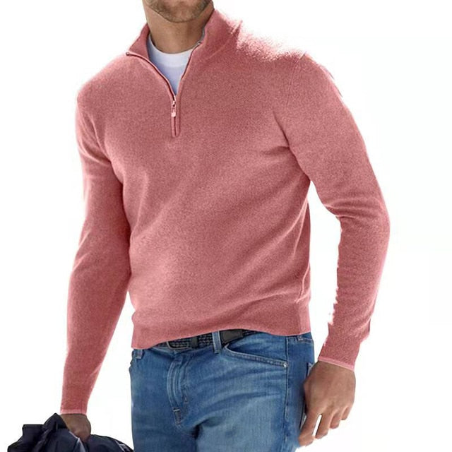 Man wearing the quarter-zip knit sweater in dusty pink, white tee underneath, with jeans and a jacket in hand.