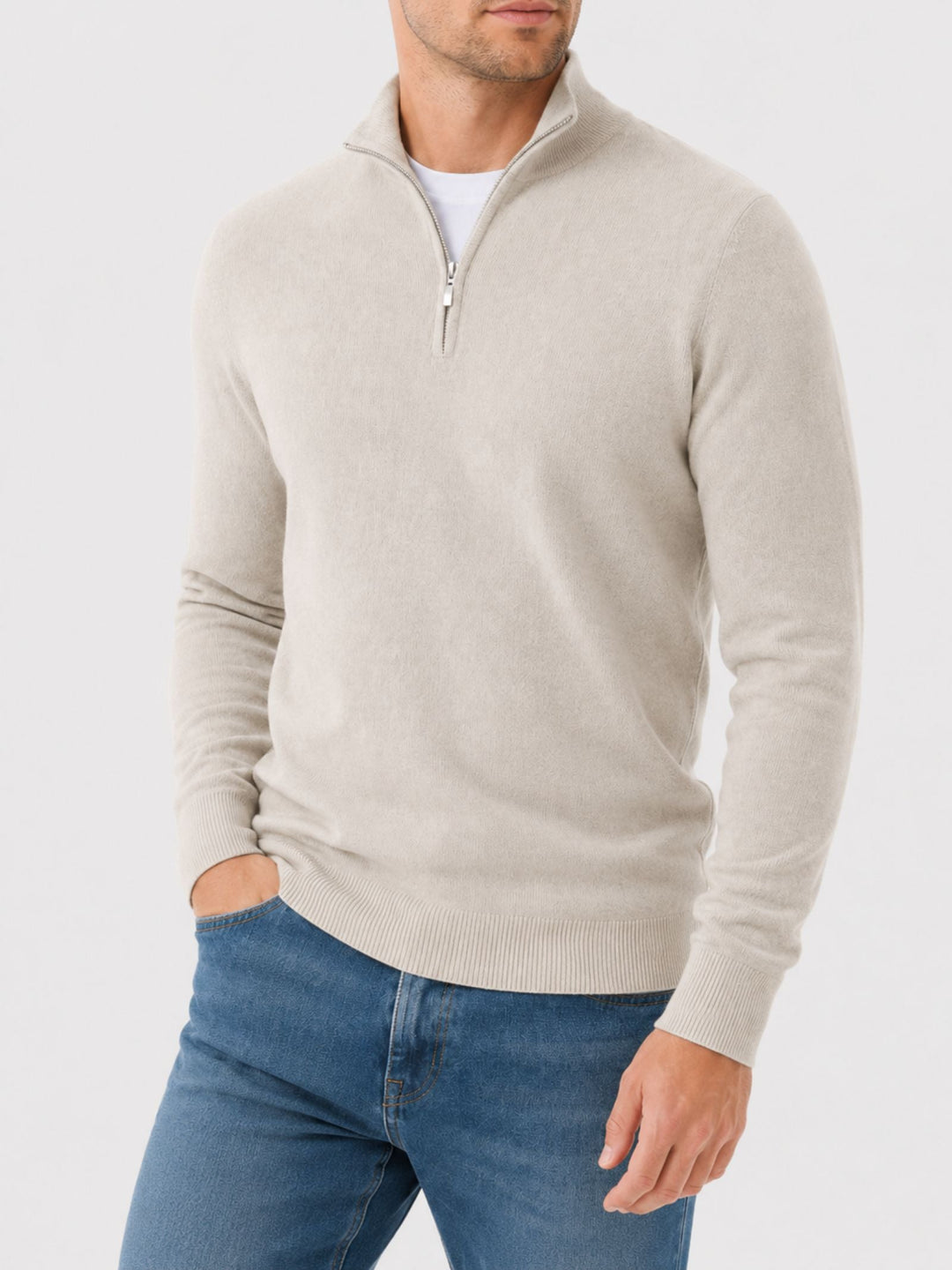 Model in a cream quarter-zip knit sweater with ribbed hem, one hand in the pocket of blue jeans.