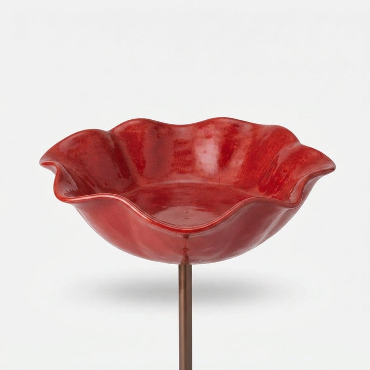 Red wavy-edged glazed bowl on a copper-toned stake.