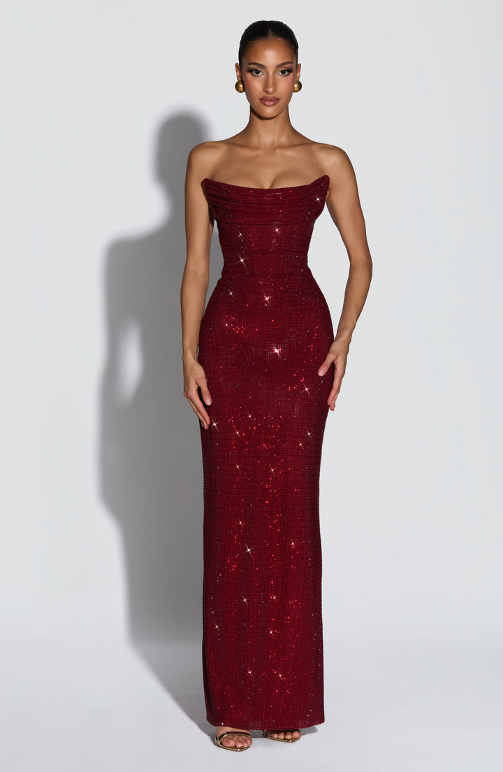 Model faces the camera in the burgundy rhinestone maxi dress with a draped strapless neckline and fitted bodice 1