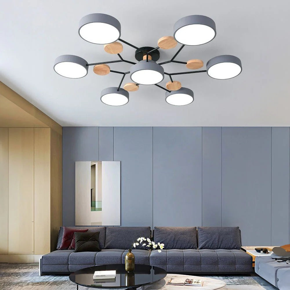 Gray seven-light chandelier in a living room with a blue-gray wall, dark sofa and round black coffee table. 10