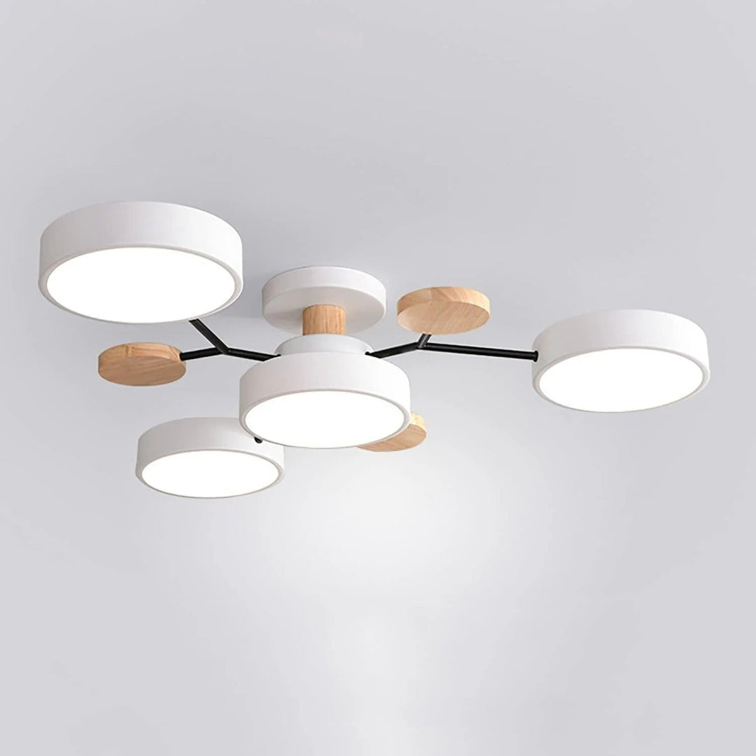 White four-light chandelier with black arms, wooden discs and a wooden stem, photographed from below on a plain background. 14