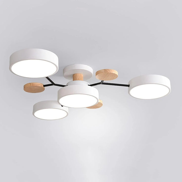 White four-light chandelier with black arms, wooden discs and a wooden stem, photographed from below on a plain background. 14