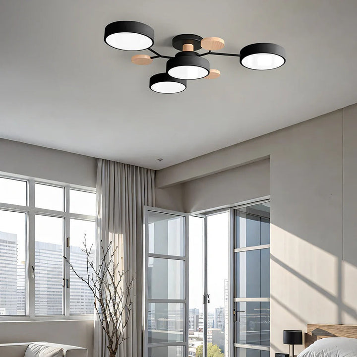 Black four-drum ceiling light in a bright bedroom with tall windows, glass doors and a city view. 26