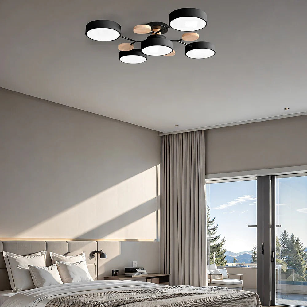 Black five-drum ceiling light in a bedroom with a large bed, beige curtains and a view of pine trees. 29