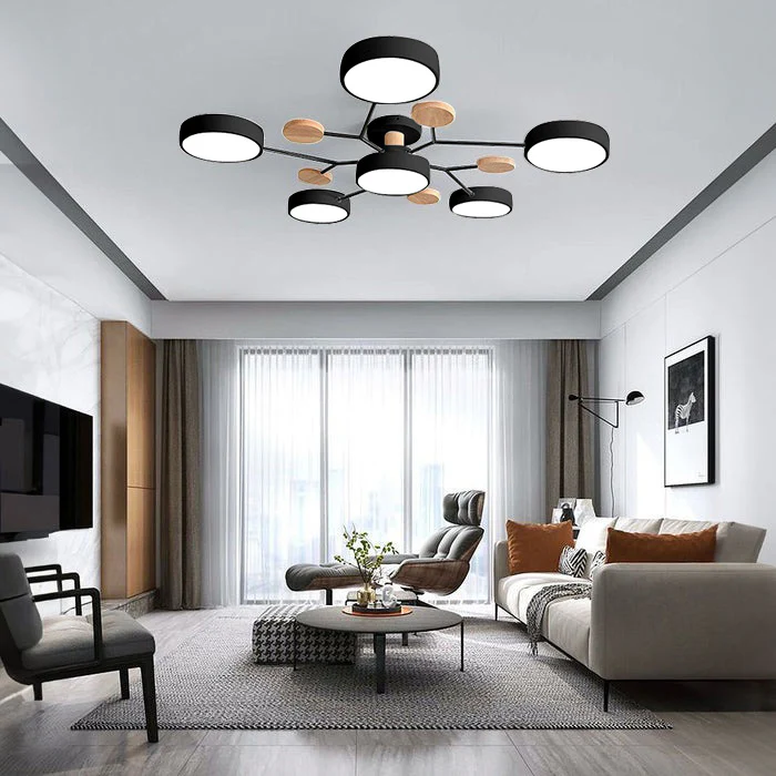 Black six-drum ceiling light with wood discs above a modern living room with a gray sofa, armchairs and round coffee table. 30