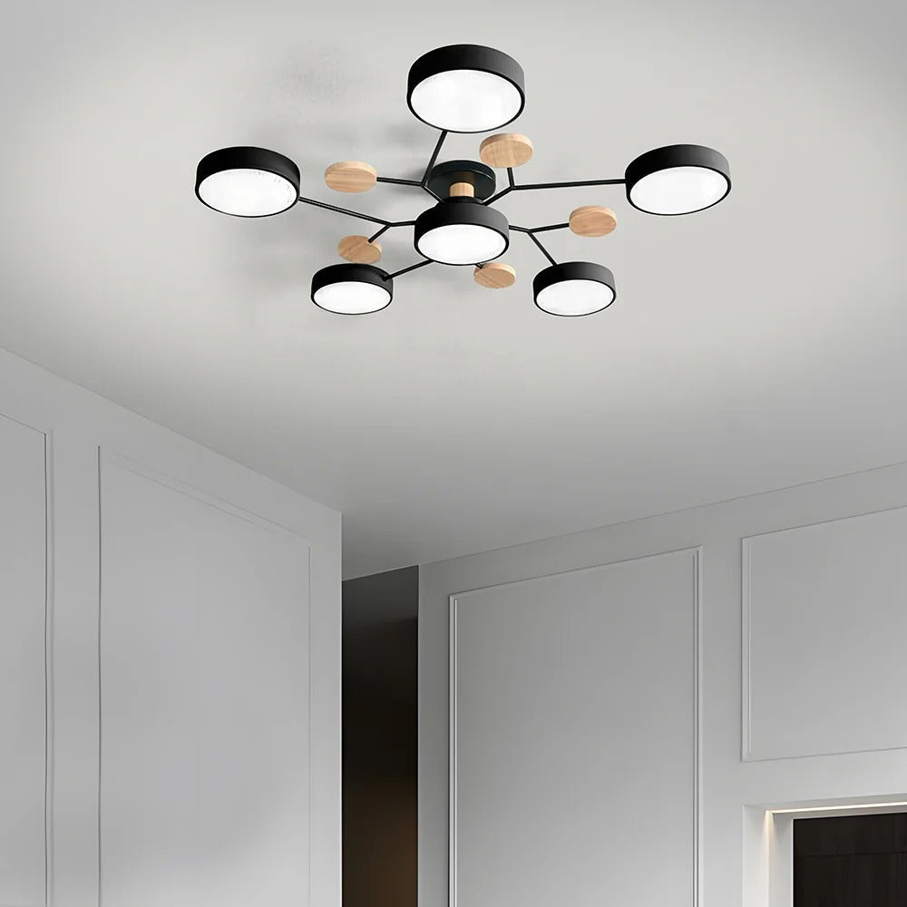 Black six-drum ceiling light with thin branching arms and wood discs on a white ceiling in a paneled room. 32
