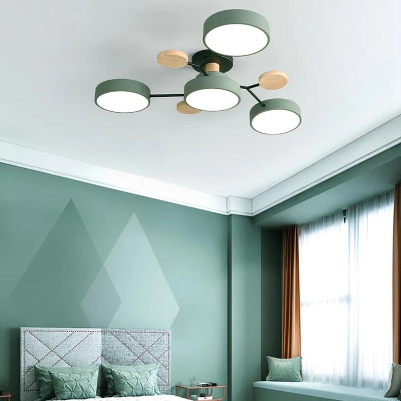 Green four-drum ceiling light with wood discs above a green bedroom with a tufted headboard and window seat. 33