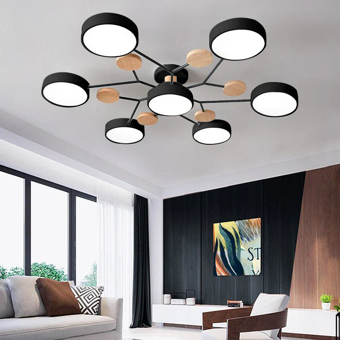 Black seven-drum ceiling light with wood discs above a living room with a white sofa and dark paneled wall. 35