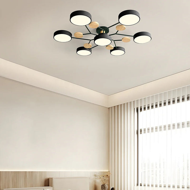 Black seven-drum ceiling light with green-tinted arms and wood discs in a cream room with vertical blinds. 36