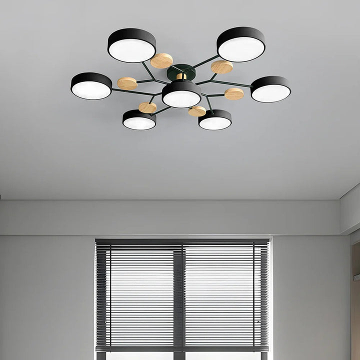 Black seven-drum ceiling light with wood discs on a gray ceiling above a window with horizontal blinds. 37