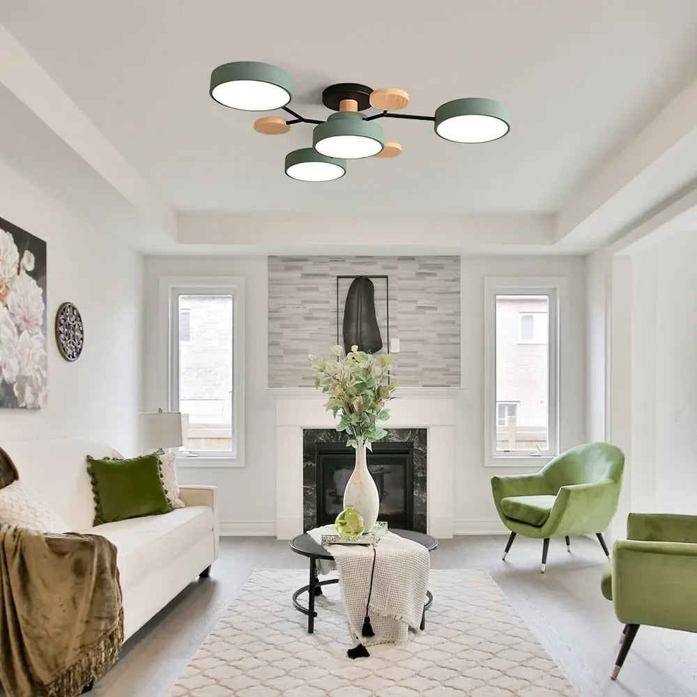 Green four-drum ceiling light in a white living room with a fireplace, green velvet armchairs and a tall vase. 39