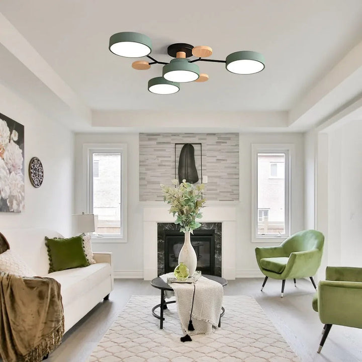 Green four-drum ceiling light in a white living room with a fireplace, green velvet armchairs and a tall vase. 39