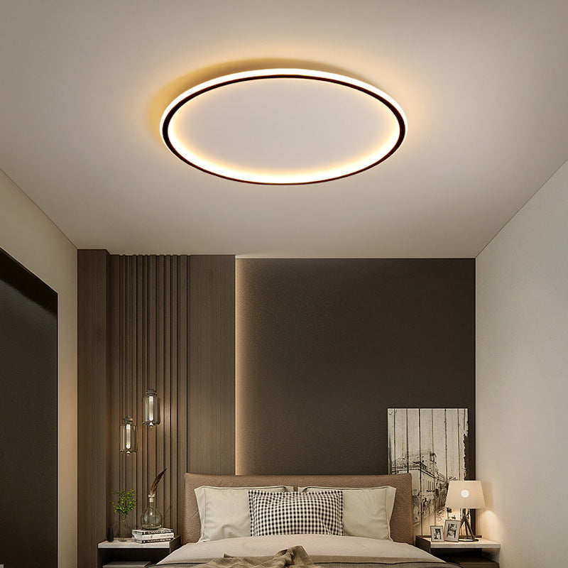 Black ring ceiling light another view in a bedroom with dark paneled walls and a checkered pillow.