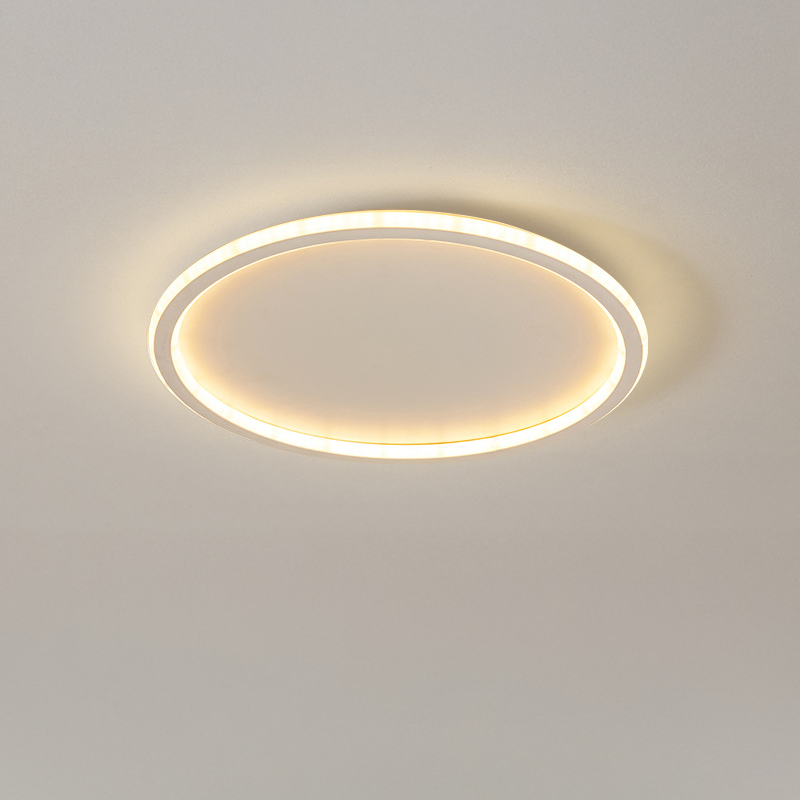 Close-up of the white ring ceiling light turned on, glowing warm with a textured diffuser on a plain ceiling.