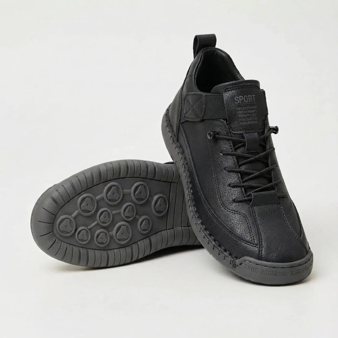 All-black grained sneakers with elastic laces, one shoe standing and one tipped to reveal the gray sole 3