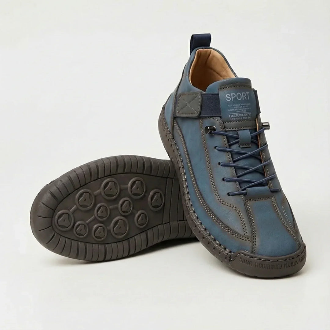 Blue sneakers with navy elastic laces and a gray strap, one shoe upright and one displaying the dark sole 6
