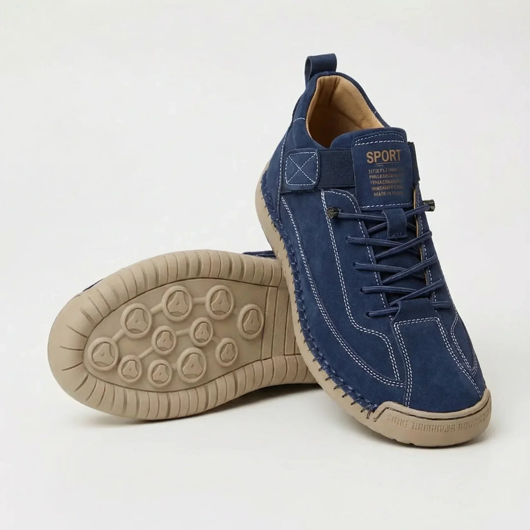 Navy suede-style sneakers with white contrast stitching and a beige sole, one shoe turned to show the tread 7
