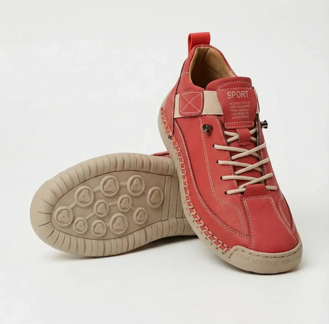 Red sneakers with cream laces, strap and stitching, one shoe standing and one tipped to show the beige sole 9