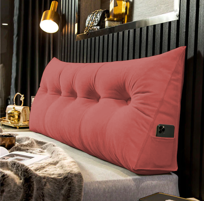 another view of a coral pink tufted velvet wedge pillow with a phone in the side pocket.