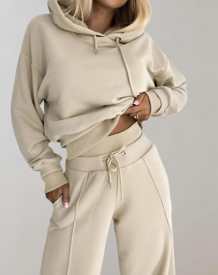 Detail of the beige set showing the hoodie drawstrings, ribbed cuffs, and the pants' ribbed drawstring waistband with front seam.