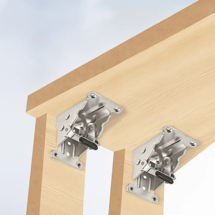 Two silver brackets mounted where light wooden legs meet the underside of a tabletop, shown in the open position. 7
