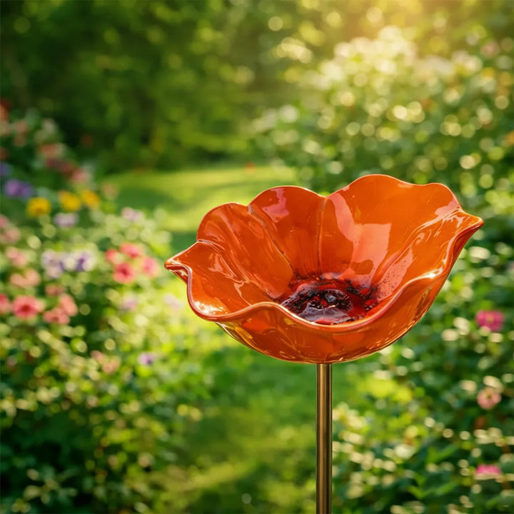 Orange glossy poppy bird bath with a dark red center on a slim stake.