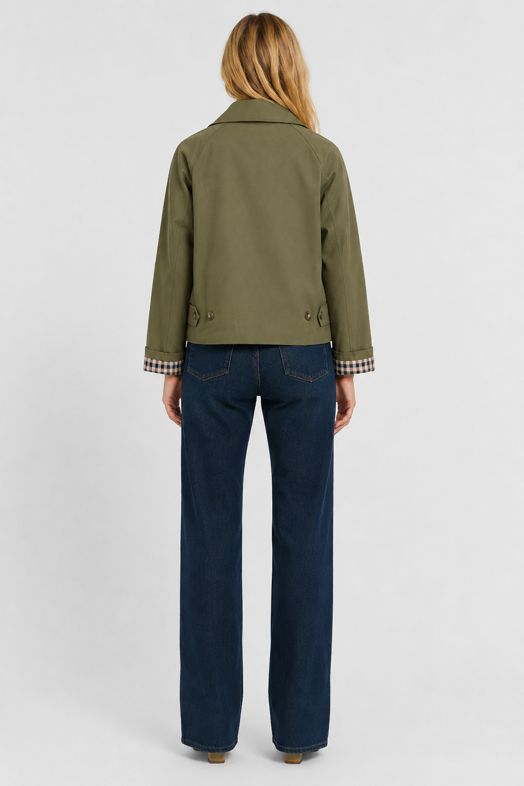 Women's olive green lightweight jacket, back view with waist tabs and gingham cuffs with dark jeans.