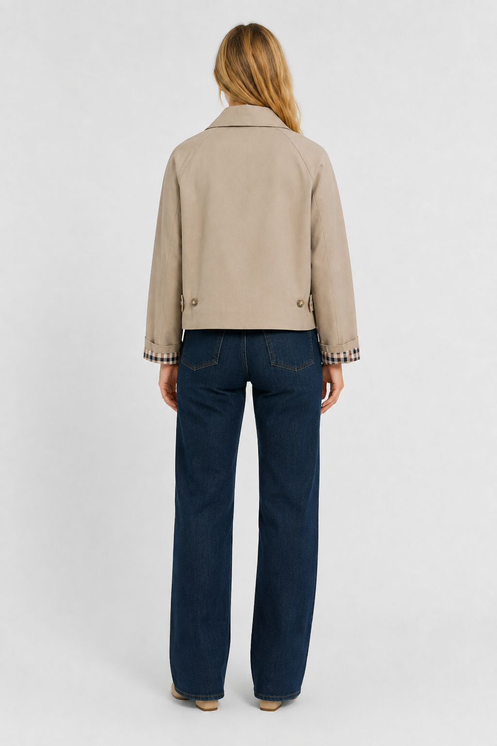 Women's beige lightweight jacket, back view with waist tabs and gingham cuffs, worn with dark jeans.