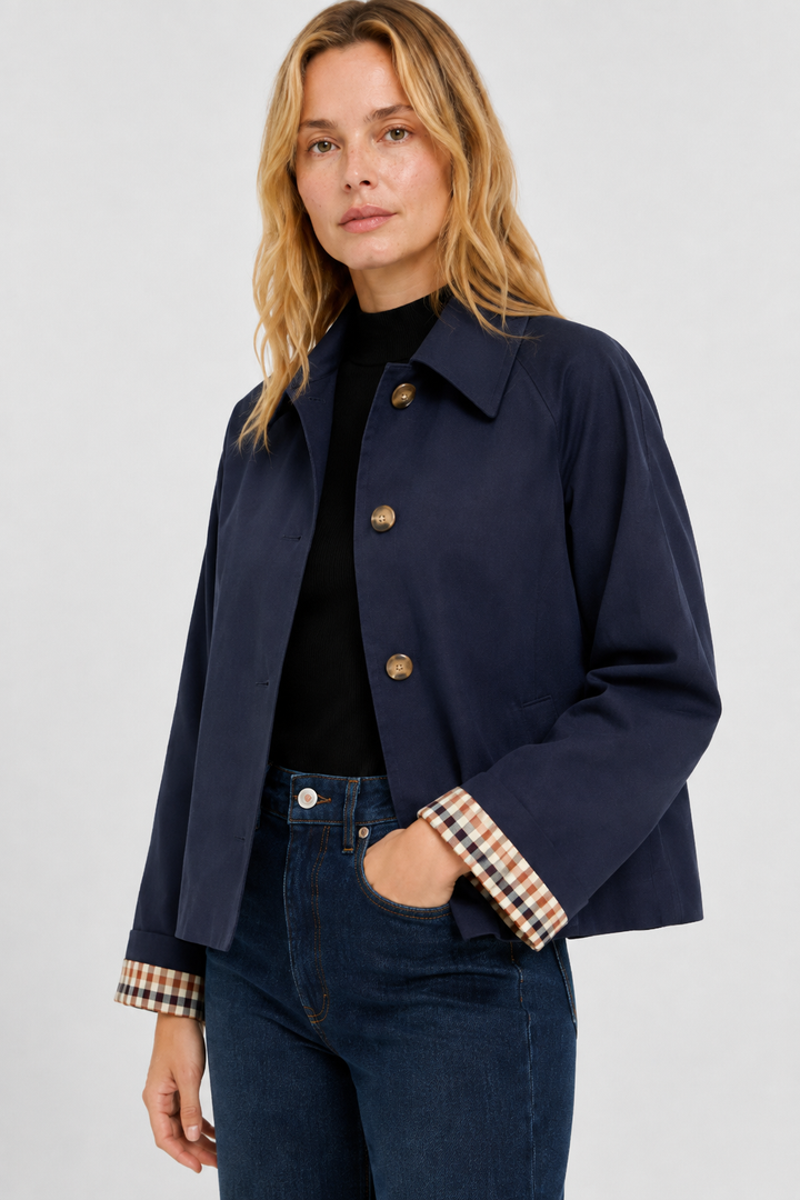 Women's navy blue lightweight jacket, another view with a hand in her jeans pocket and checked cuff lining.