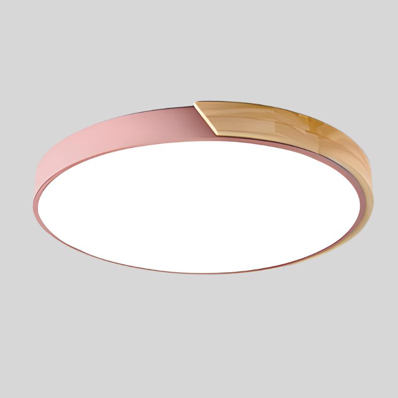 Pink round ceiling light with a natural wood segment on the rim and bright white diffuser, product shot on a gray background.