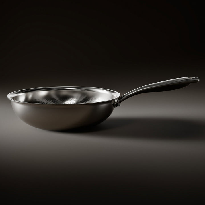 Side view of the wok pan on a dark surface, showing its rounded bowl, flat base and long steel handle. 2