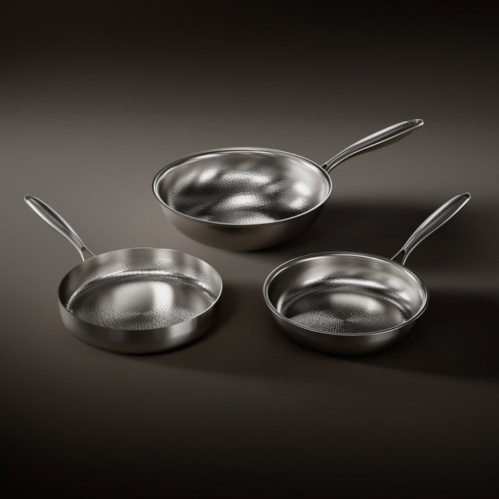 Three hammered titanium pans with steel handles, seen from above