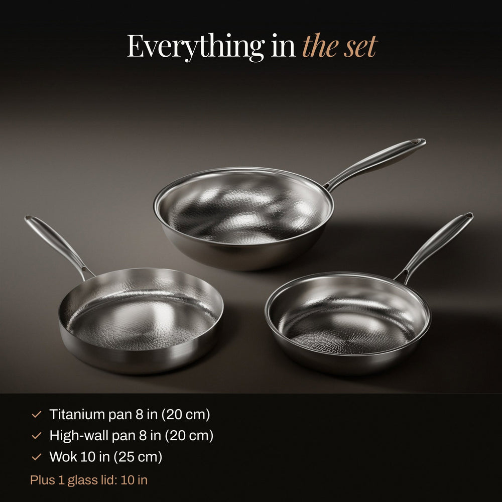 The full hammered titanium pan set laid out on a dark background