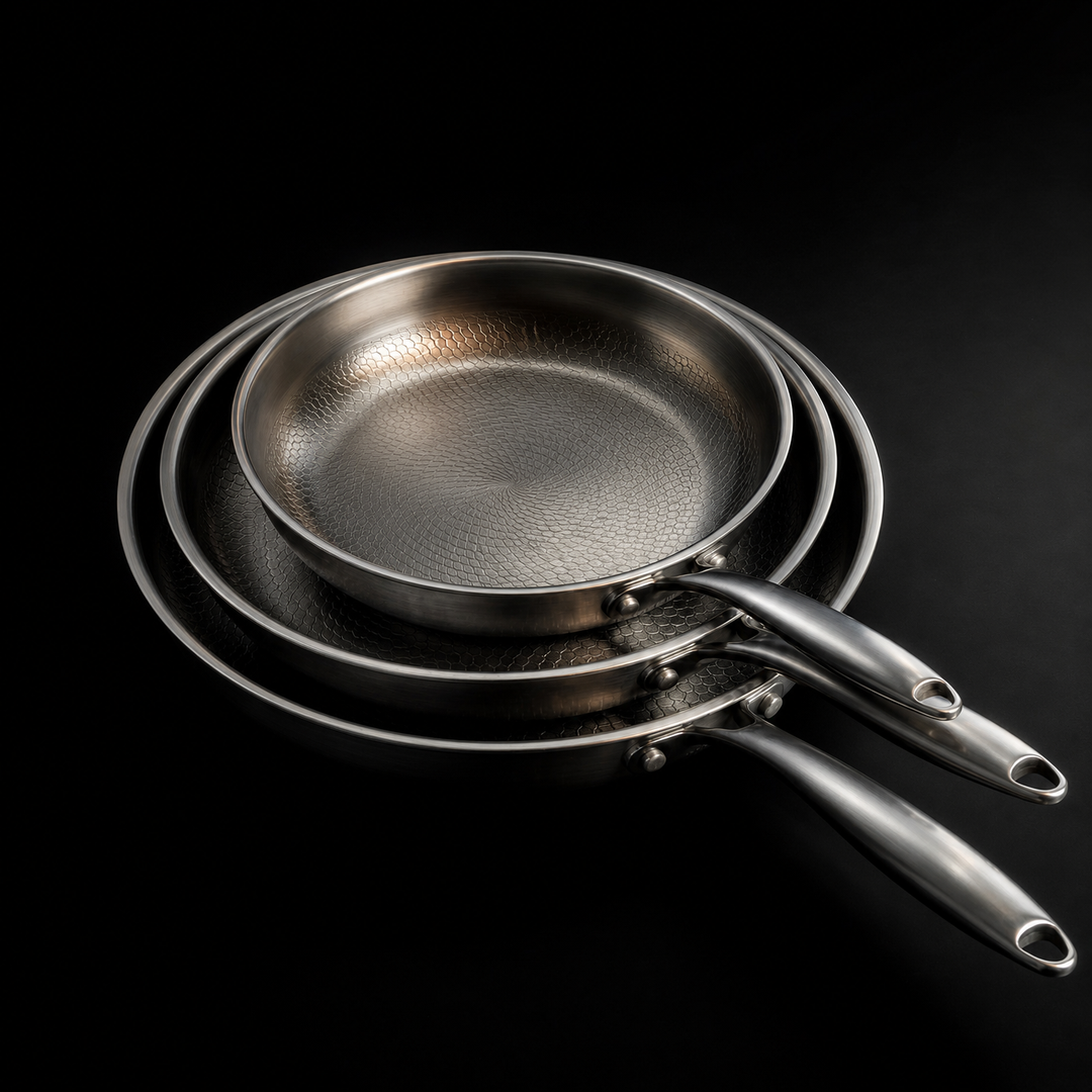 Three stacked pans from above at an angle, showing the hammered pattern inside each pan and the brushed handles.