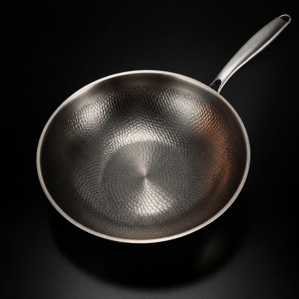 Top-down view of the hammered titanium wok pan interior with the handle at upper right.