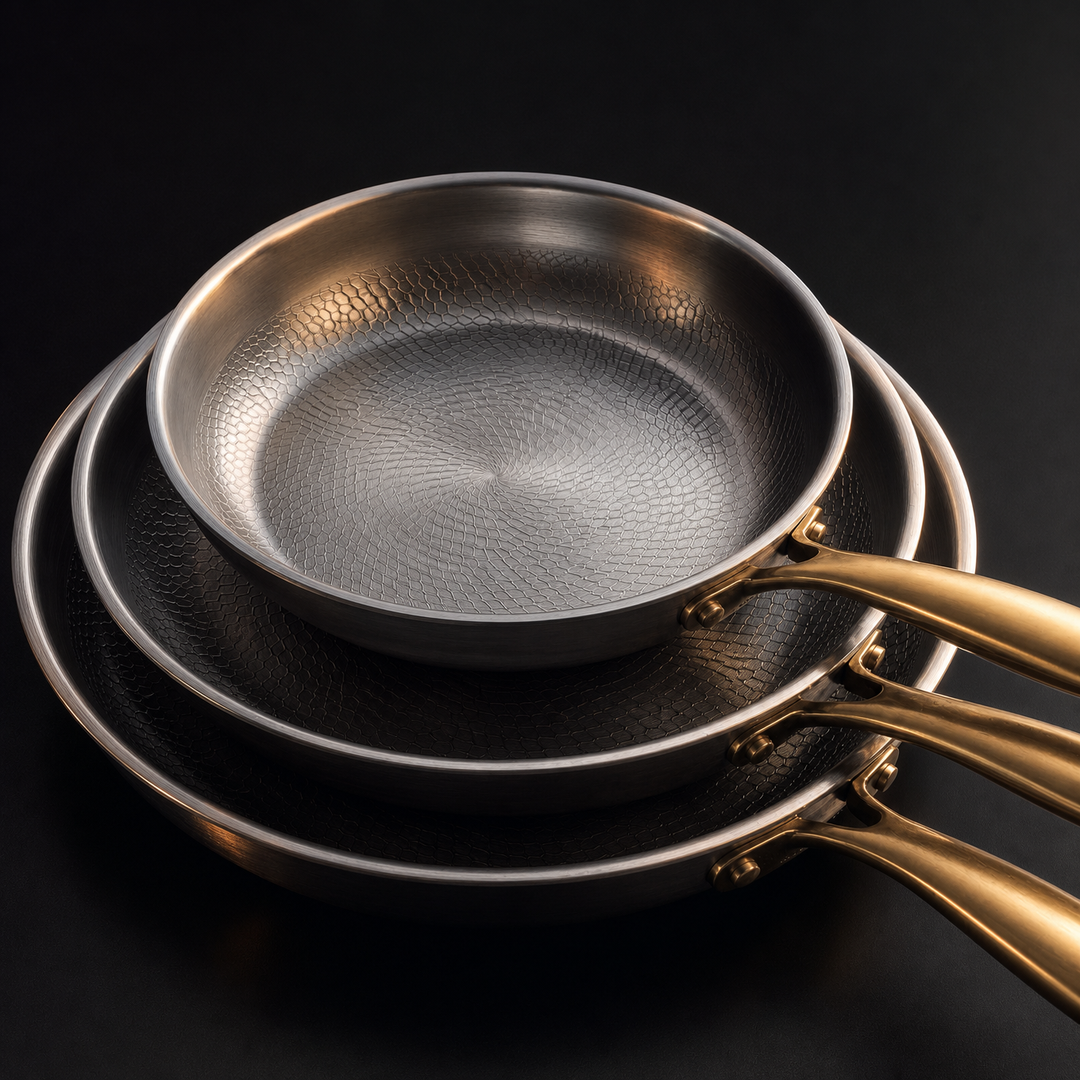 Close-up detail of the stacked pans showing the textured cooking surface, rolled rims and riveted gold-toned handles.